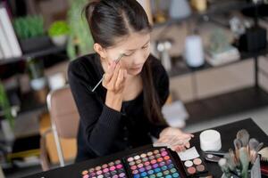 beauty Asian woman applying make up foundation and concealer make up on face with cosmetics makeover Daily routine at home. photo