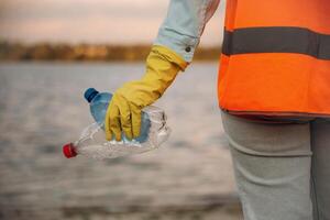 Trash,, pollution. Close up view of female ,volunteer that is holding plastic bottle. photo