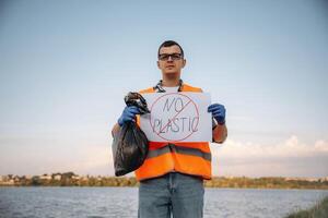 Text 'no plastic', on poster... Man volunteer is against Earth pollution by trash, outdoors photo