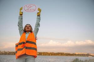 Hands ,holding,, banner with 'no plastic' text on it. Woman volunteer is against trash pollution outdoors photo