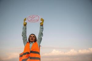 Hands holding banner with ,,'no plastic' text on it. Woman volunteer is against trash pollution outdoors photo