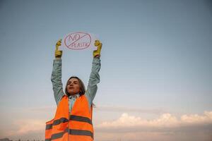 Hands, holding ,banner ,with 'no plastic' text on it. Woman volunteer is against trash pollution outdoors photo