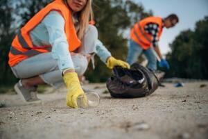 A volunteers, collects ,,garbage on a muddy beach photo