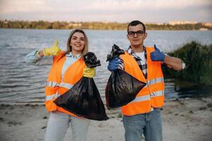 Showing fingers up, smiling,,, finished. A volunteers collects garbage on a muddy beach photo