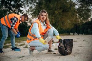 A volunteers ,,collects garbage, on a muddy beach photo