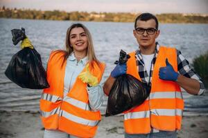 Showing ,fingers, up, smiling, finished. A volunteers collects garbage on a muddy beach photo
