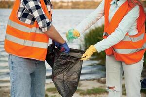 With trash, bags. A volunteers,, collects garbage on a muddy beach photo