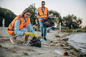 On ,the, shore. A volunteers collects garbage on a muddy beach photo