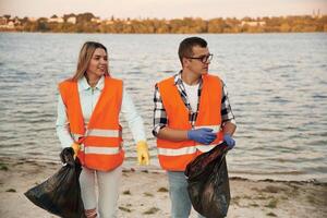A ,volunteers, collects garbage on a muddy beach photo