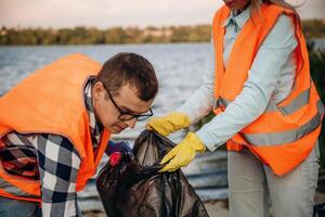 With trash ,,bags. A volunteers collects garbage on a muddy beach photo