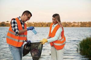 With ,trash, bags. A volunteers collects garbage on a muddy beach photo