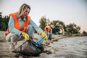 On the shore... A volunteers collects garbage on a muddy beach photo