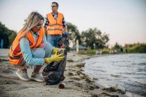 On the shore.. A volunteers collects garbage on a muddy beach photo