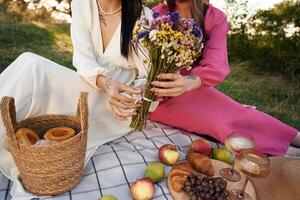 Fruits,, flowers and glasses of drink. Lesbian couple is together on the picnic in nature photo
