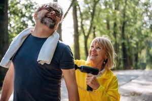 An electric massager. Using by woman ,,,for a man. Senior couple together outdoors at nature photo