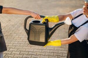Two women are holding watering can in hands, conception of gardening. photo