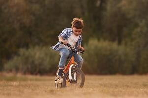 Cute boy is with his bicycle on the field. photo