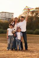 Family of ,father,, mother, daughter and son that are standing in the field, with kite in hand photo