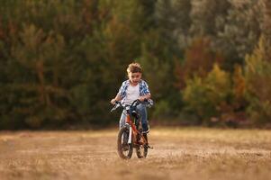 Riding, having fun.,, Cute boy is with his bicycle on the field photo