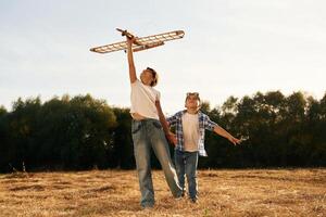 Having fun. Boy ,and girl are playing with wooden toy plane on the field photo