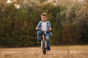 Riding,, having fun... Cute boy is with his bicycle on the field photo
