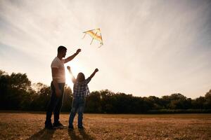 Father and ,son ,are with kite on the field, illuminated by sunlight photo