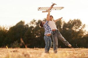 Having fun. Boy, and girl are playing with wooden toy plane on the field photo