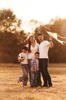 Vacation time..., Family of father, mother, daughter and son that are standing in the field, with kite in hand photo