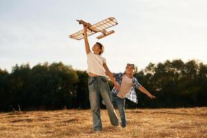 Having ,,fun. Boy and girl are playing with wooden toy plane on the field photo