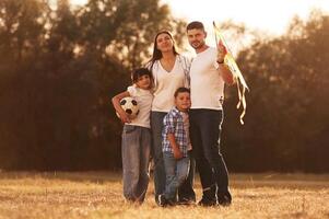 Vacation, time. Family of father, mother, daughter and son that are standing in the field, with kite in hand photo