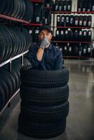 Fun,,,,,, pretending to dive inside the wheels. Man worker is maintenance station with tires photo