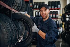 Friendly ,facial expression,,, in cap. Man worker is maintenance station with tires, wheels photo