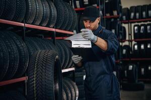 Black ,colored ,notepad, information, documents. Man worker is maintenance station with tires, wheels photo