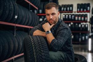 Thinking, sitting... Man worker is maintenance station with tires, wheels photo