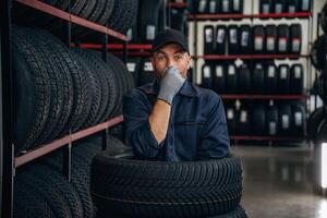 Fun,, pretending,, to dive inside the wheels. Man worker is maintenance station with tires photo
