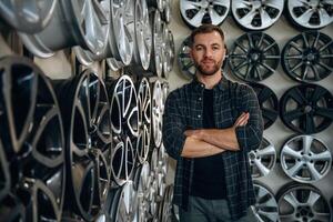 Standing wit,,,h arms, crossed. Man worker is maintenance station with tires, wheels photo