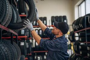 On, the shelve, taking the tire. Man worker is maintenance station with tires, wheels photo