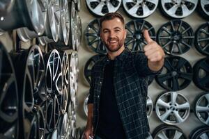 Thumb, up, gesture. Man worker is maintenance station with tires, wheels photo