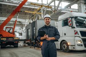 Front view,, holding, notepad,, standing. Male worker is in the modern warehouse or manufacturing company photo