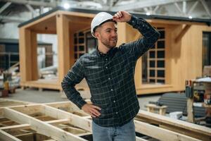 Looks, far,,, away. Male builder is at construction of wooden house photo
