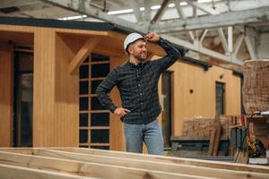 Looks far ,,,away. Male builder is at construction of wooden house photo