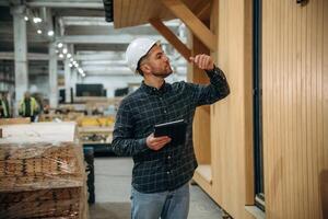 Digital, tablet is in hand. Male builder is at construction of wooden house photo