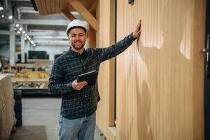 Digital tablet ,,is in hand. Male builder is at construction of wooden house photo