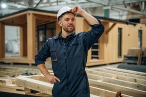 Looks, far, away. Male builder is at construction of wooden house photo