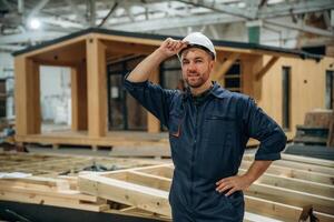 Looks ,,far away. Male builder is at construction of wooden house photo