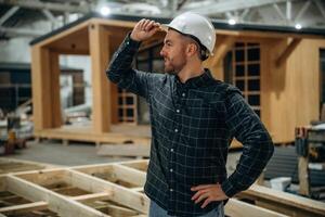 Looks, far away. Male builder is at construction of wooden house photo