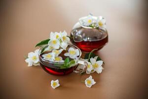 Natural green tea with jasmine petals on a brown background . photo