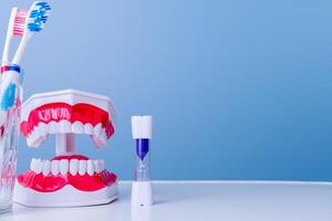 Dental hygiene tools with toothbrush, model dentures, and timer on blue background photo