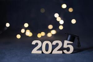 Wooden number 2025 with graduated cap on dark background with bokeh. Class of 2025 concept photo