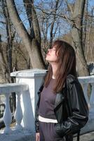 Woman enjoying the sunny day while gazing towards the sky among bare trees in a serene outdoor setting photo